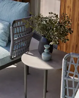 CURIO Armchairs and Side Table positioned on a stylish outdoor patio with lush greenery.