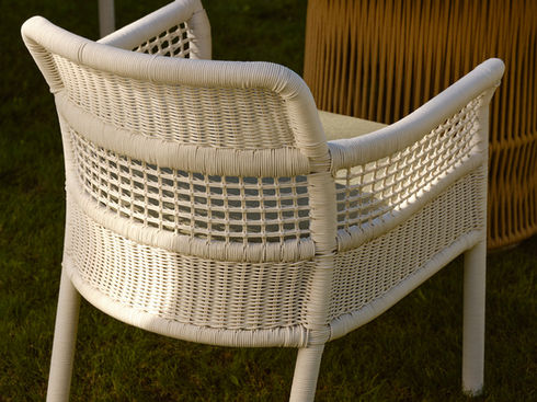 Rear view of a white ESCALA Dining Armchair beside an outdoor table