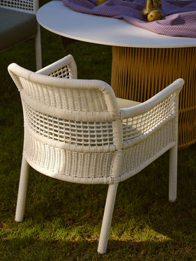 Rear view of a white ESCALA Dining Armchair beside an outdoor table