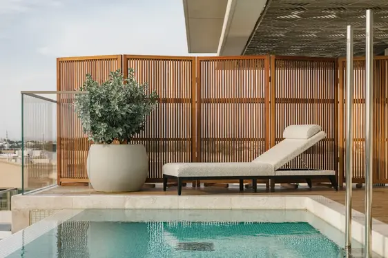 Chuchumber sun lounger beside private plunge pool, framed by timber privacy screens and planters in Dubai.