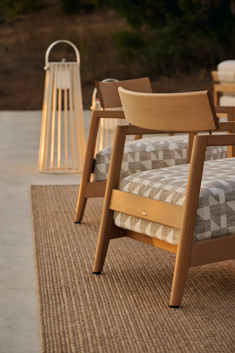 Close-up of Kubik outdoor chair with curved backrest, patterned cushion and warm TechTeak frame.