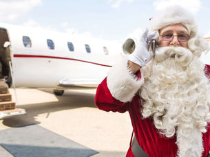 Santa Claus beside a private jet making a call to book holiday private jet travel — festive image for Mach Point Aviation holiday charter blog.