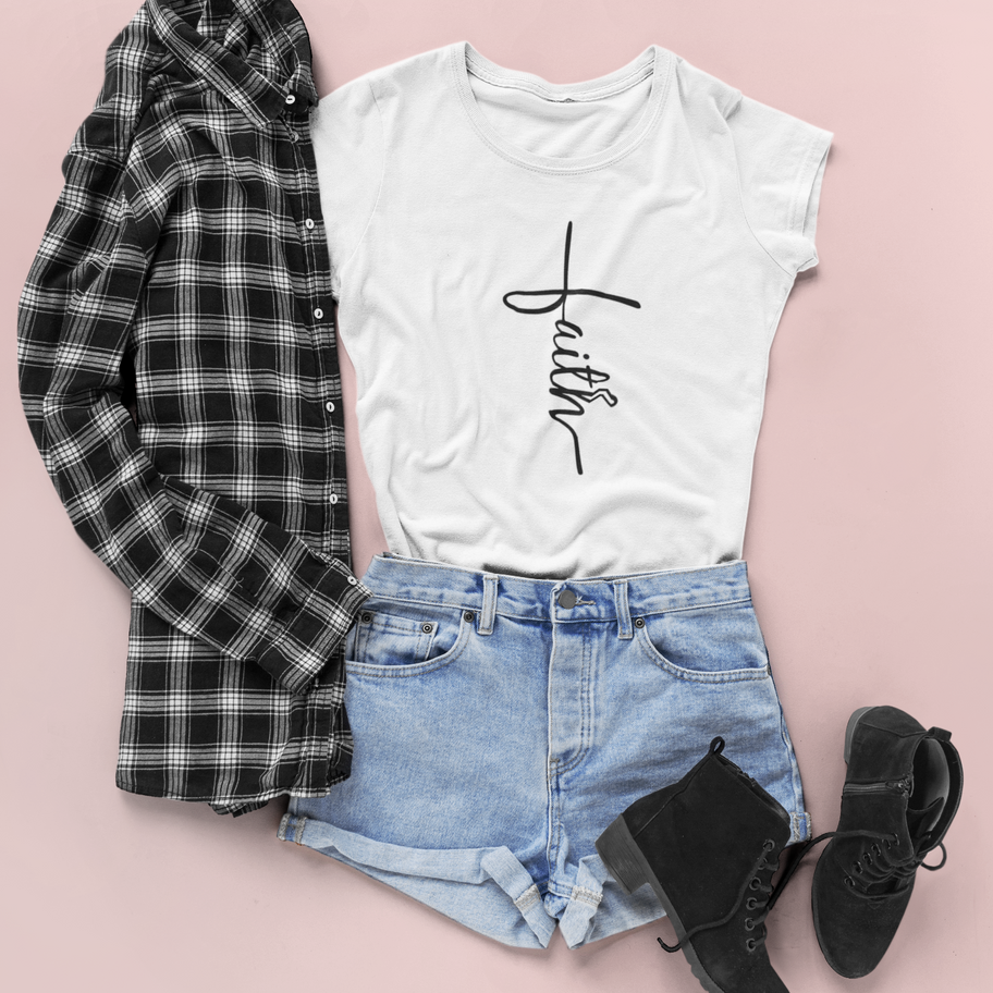 Flat lay of a white "faith" T-shirt with denim shorts and a plaid shirt.