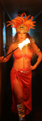 Fire dancers dressed in orange tribal Aztec themed costume holding a fire prop