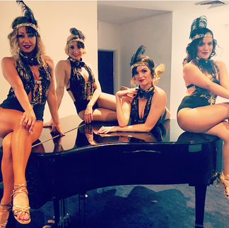 Four Gatsby dancers sitting on a piano at a wedding in Sydney