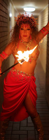 Fire dancers dressed in red Aztec themed costume holding a fire prop