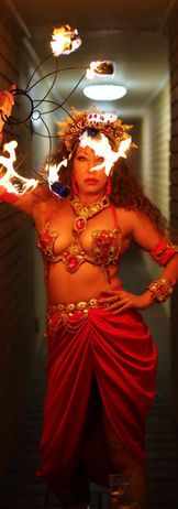 Fire dancers dressed in red aztec themed costume holding a fire fan prop