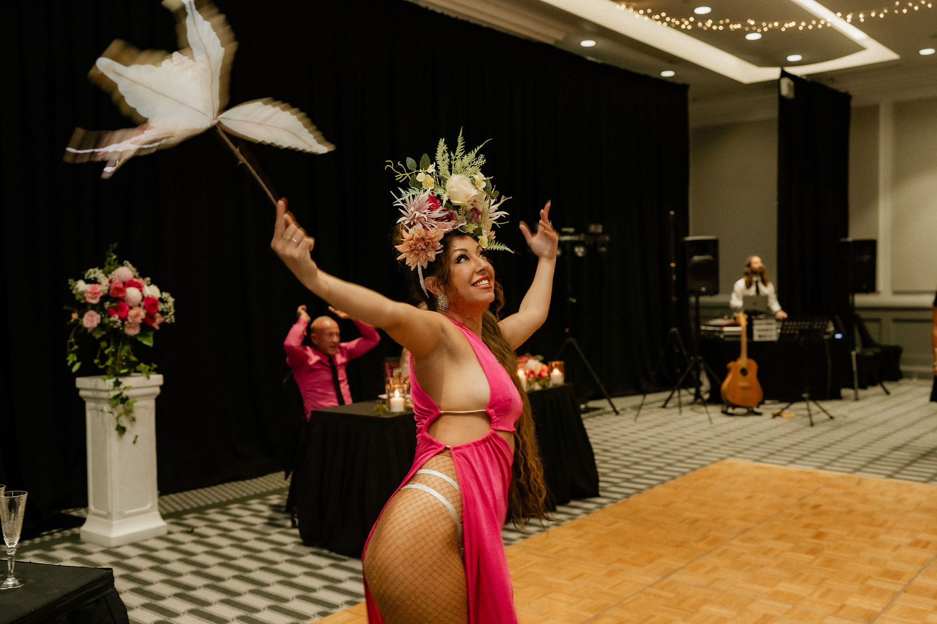 Roving perfomer dressed in pink gown and floral headpiece dancing at wedding reception
