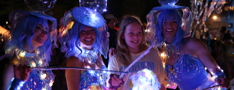 three performers dressed as Glowing jellyfish posing with a child at kids parties