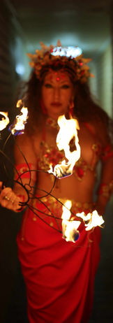 Fire dancers dressed in red Aztec themed costume holding a fire prop