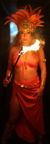 Fire dancers dressed in orange tribal Aztec themed costume holding a fire prop