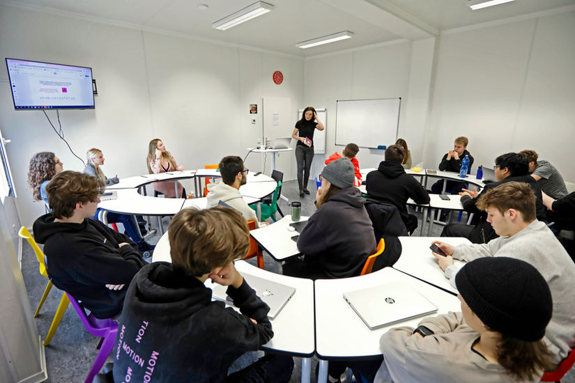 Studenti ve třídě sedící po skupinách.