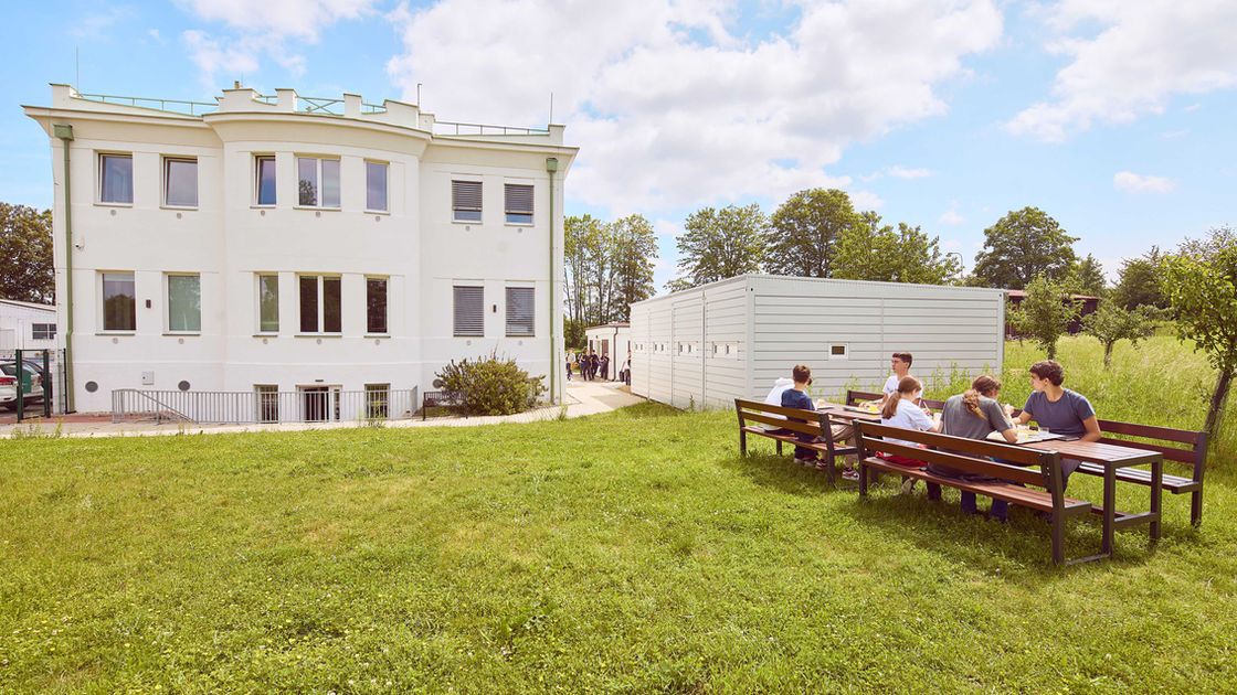 Budova školy a venkovní posezení.