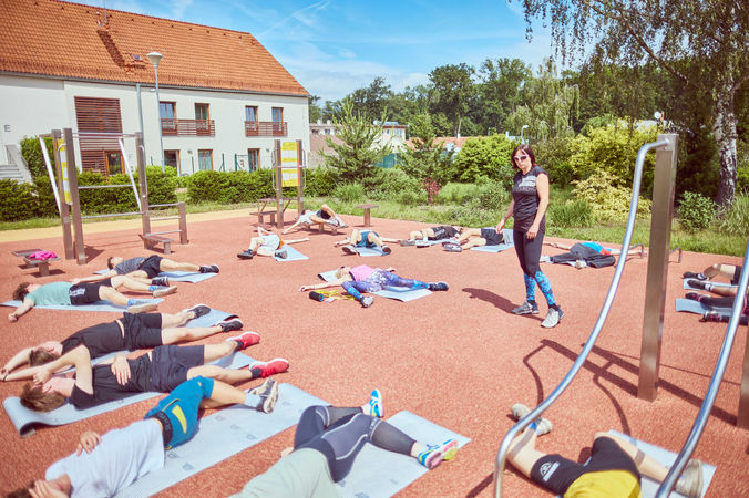 Studenti během sportovní výuky ležící na zemi.