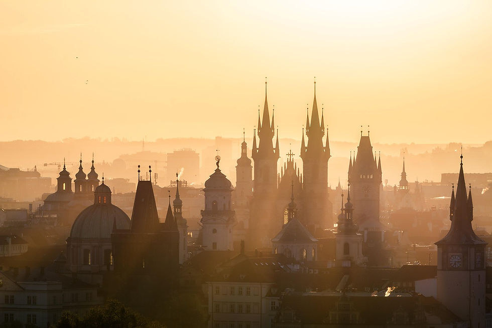 Silhouetted spires and domes of a city skyline at sunrise, bathed in golden light, creating a serene and majestic atmosphere.
