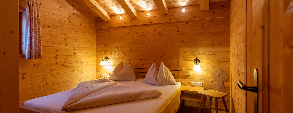 Schlafzimmer des Chalets mit Doppelbett und viel Holz