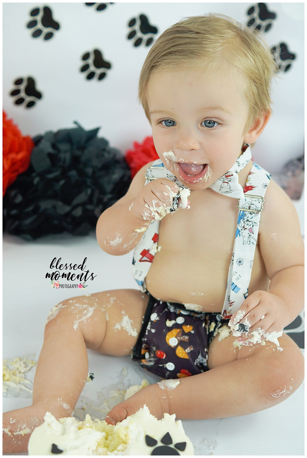 1 year old boy eating cake in dalmatian suspenders and boy tie