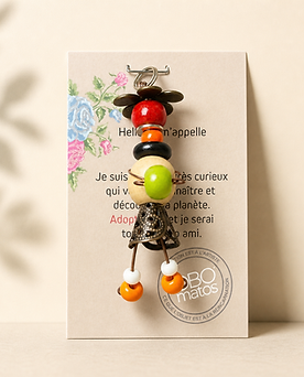 Figurine Obo ‘Celle qui en rajoute une couche’, création artisanale en perles colorées avec pompons roses et éléments métalliques, pièce unique faite main