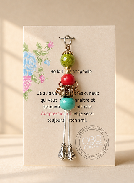 Figurine Obo ‘Celui qui fait pencher la balance’, création artisanale en perles vertes, rouges et turquoises avec éléments métalliques, assemblage vertical équilibré, pièce unique faite main