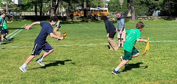 Boys running with batons on soccer field on sunny day