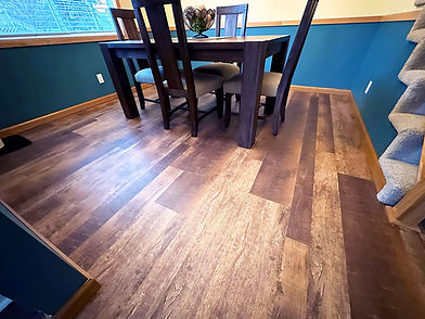 Natural looking vinyl planks installed in a dining room with blue walls.