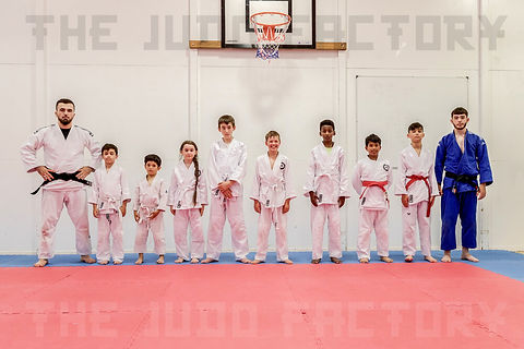 A row of young judo students with a coach at either side