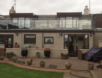 Rear view of a house with a balcony terrace and stone patio garden
