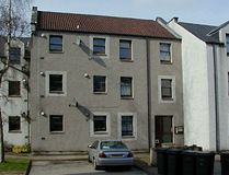 Three storey apartment block with grey render and uniform dark window frames