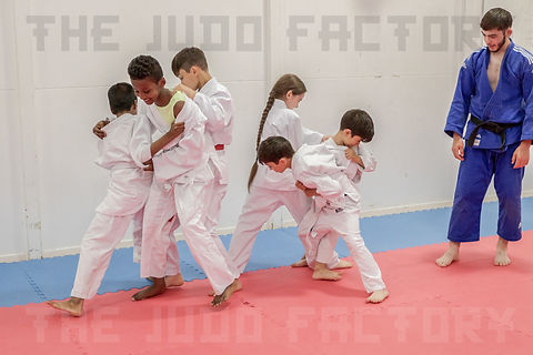 Children practising judo while the coach watches