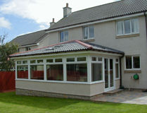 Wrap around sunroom extension with dark frames and large glass panels