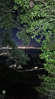 Visual da cidade iluminada durante subida noturna ao Cambirela
