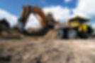 An excavator at a construction site digging into the ground