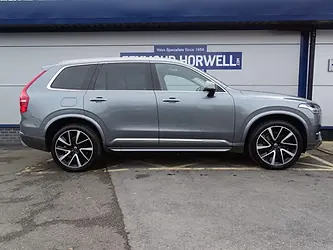 A side view of a gray Volvo SUV parked in front of a dealership