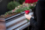 A girl holding a red rose behind a coffin, symbolizing love, loss, and farewell during a somber funeral ceremony