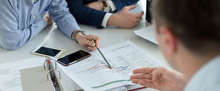 Professionals in a meeting analyzing a graph on a document