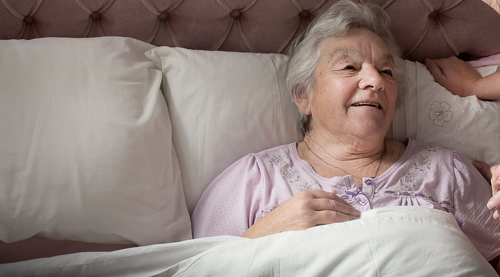 Personal care assistant chatting to a senior woman in bed