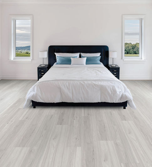 Contemporary bedroom featuring Whisper Wood AQ517 AquaPro Max 15mm waterproof laminate flooring by Lago Flooring with light wood styling for luxury residential interiors and designer spaces.