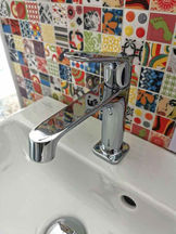 Tap in front of multi-coloured tiles