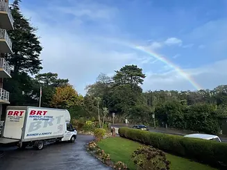 B R T Removals van parked with a rainbow in the sky