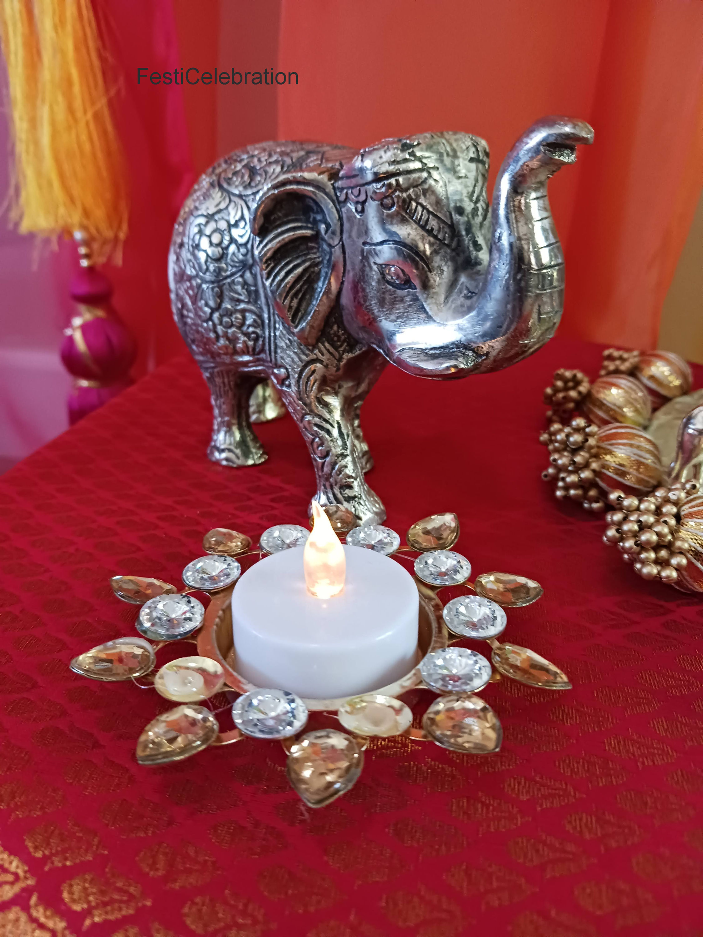 Decorative elephant and candle holder on red cloth.