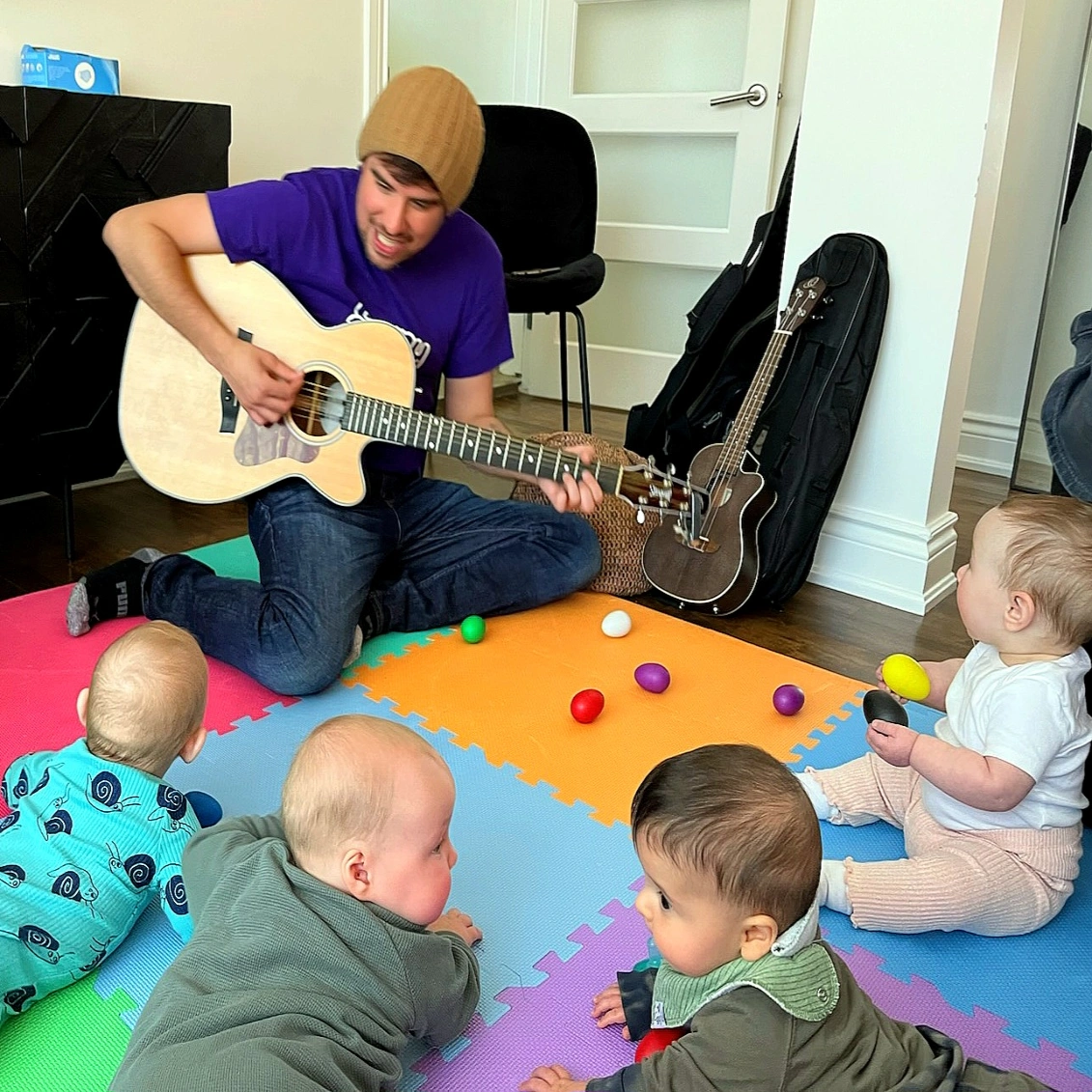 Shawny playing guitar with a group of infants around him