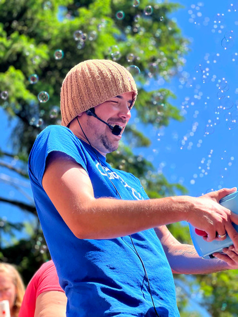 Shawny holds a bubble machine, wearing a blue shirt