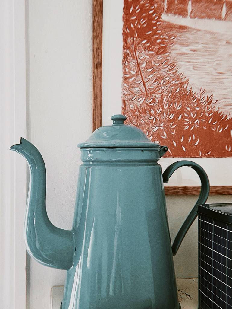 Close-up of a Danish vintage blue teapot against a framed artwork in warm tones