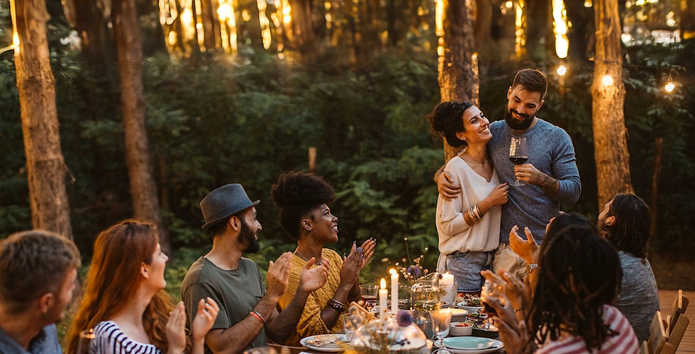A group of people enjoying a meal outdoors, gathered around a rustic dining table.