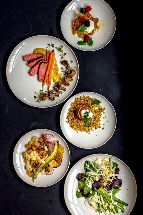 Variety of plated dishes including steak with carrots, couscous, roasted vegetables, and salad