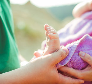 father-holds-feet-his-child-enveloped-violet-towel.jpg
