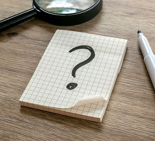Question Mark on Graph Paper Notepad on Wooden Surface.jpg