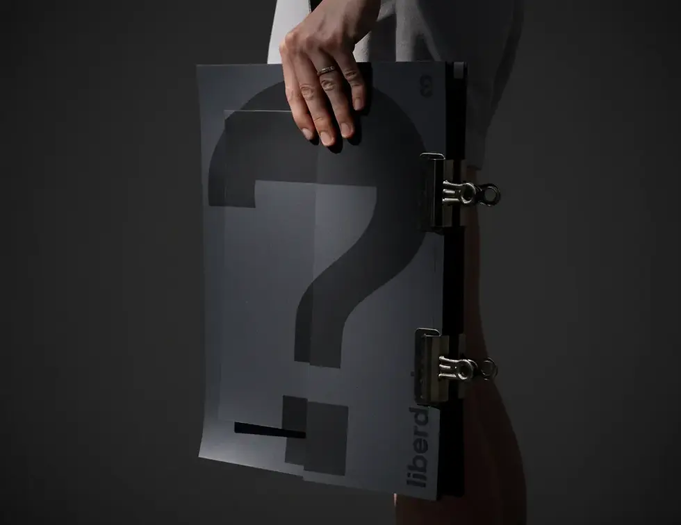 Person holding a dark folder with a gradient question mark and metal clips, set against a black background.