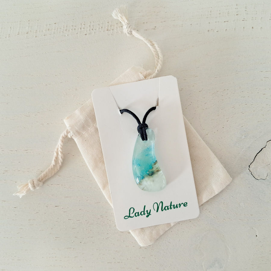 Thumbnail: Glazen hanger met Caribisch zeegezicht, met aquablauwe en witte tinten. Hanger hangt aan zwart waxkoord.