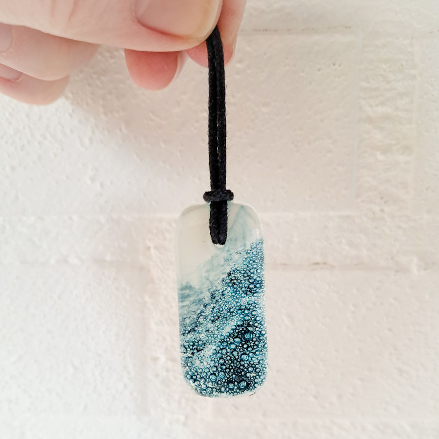 Thumbnail: Glazen hanger met zeegezicht, donkere woeste golven met bubbels in het glas aan de ene kant en wit zeeschuim aan de andere ka
